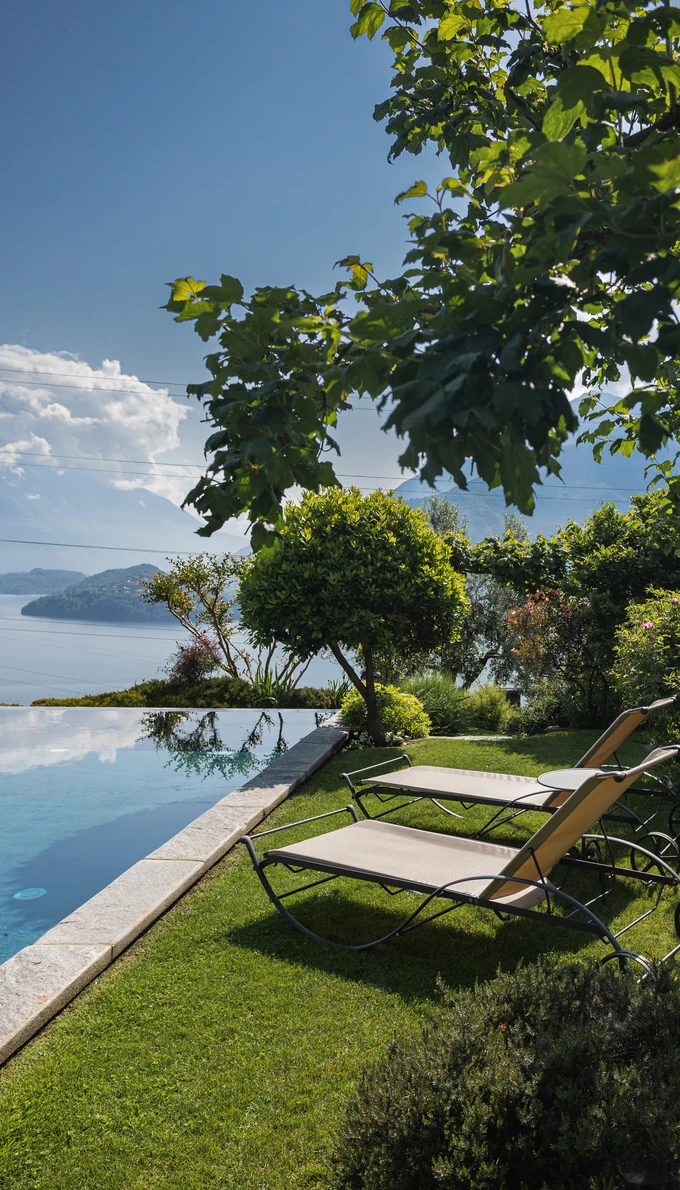 Sun loungers on the lawn beside the infinity pool, with Lake Como in the distance