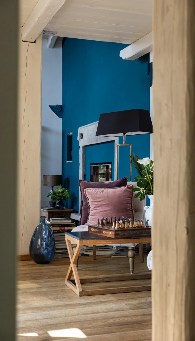 Sitting room with a blue wall, a chessboard on the coffee table and wooden floors