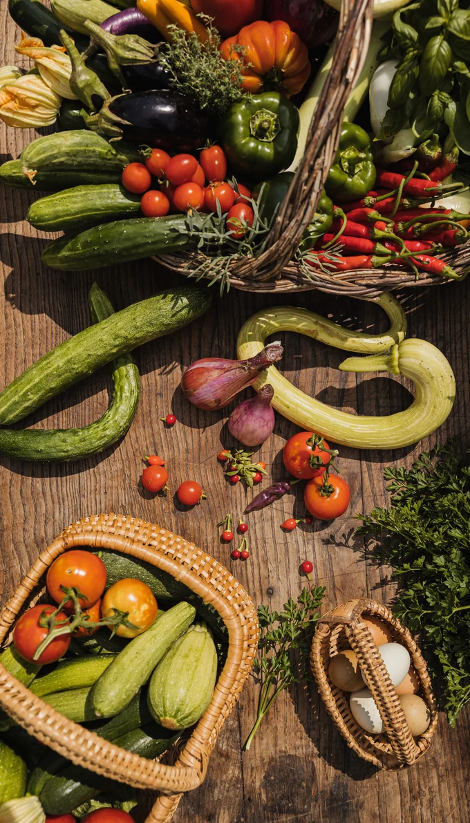 Baskets of fresh vegetables, tomatoes and eggs on a wooden table